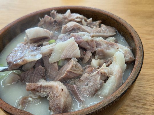 갈색 뚝배기에 머리고기를 수북하게 담은 돼지머리국밥, 뽀얀 국물